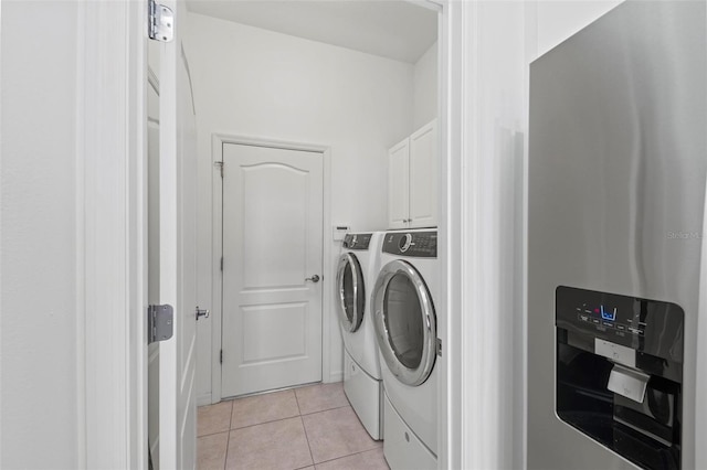 laundry area featuring cabinets, light tile patterned floors, and washing machine and clothes dryer