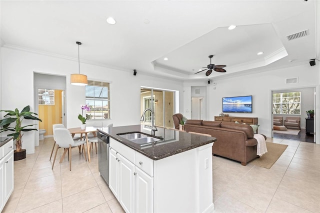 kitchen featuring pendant lighting, sink, white cabinets, a tray ceiling, and a center island with sink