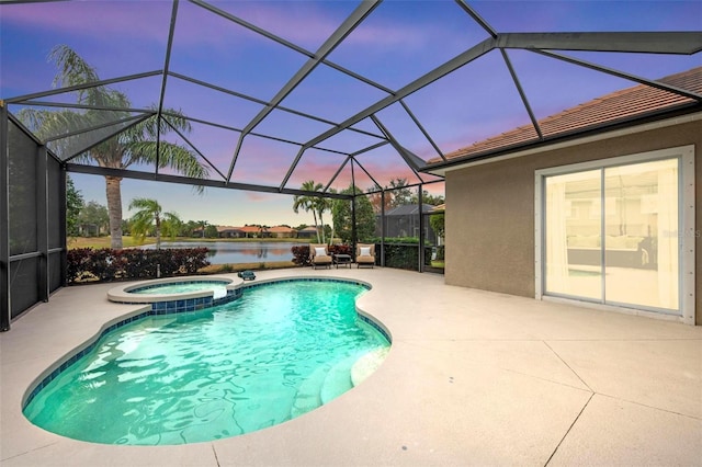 pool at dusk featuring an in ground hot tub, glass enclosure, a patio area, and a water view