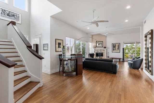 living room with hardwood / wood-style flooring, plenty of natural light, ceiling fan, and a high ceiling