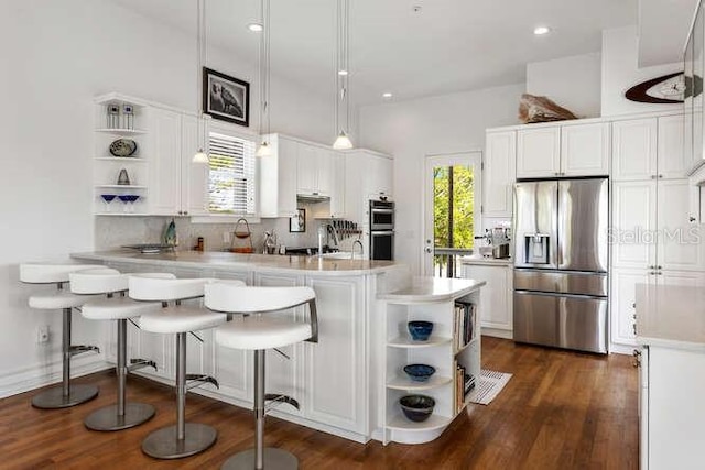 kitchen featuring appliances with stainless steel finishes, white cabinetry, hanging light fixtures, decorative backsplash, and kitchen peninsula