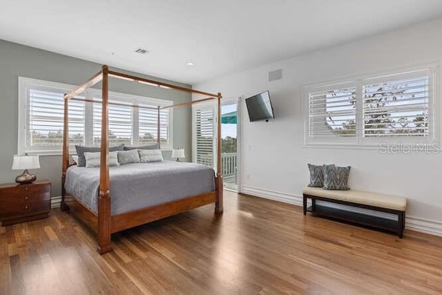 bedroom with multiple windows and hardwood / wood-style flooring