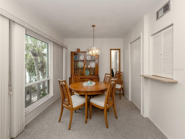 carpeted dining space with a chandelier