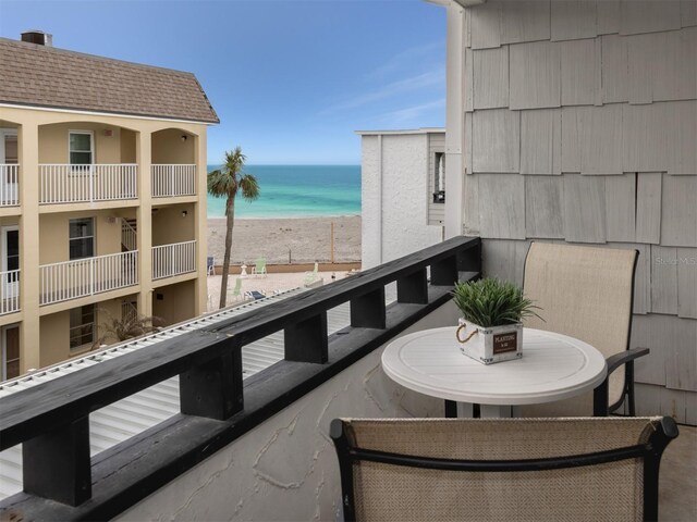 balcony with a water view and a view of the beach