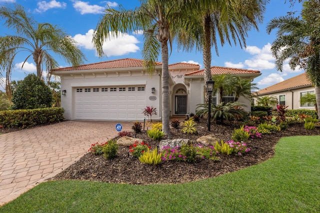 mediterranean / spanish home featuring decorative driveway, stucco siding, a tiled roof, and a garage