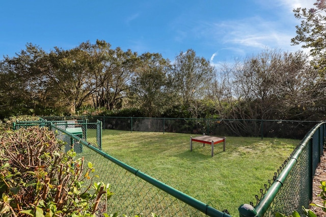 view of property's community featuring a lawn and fence