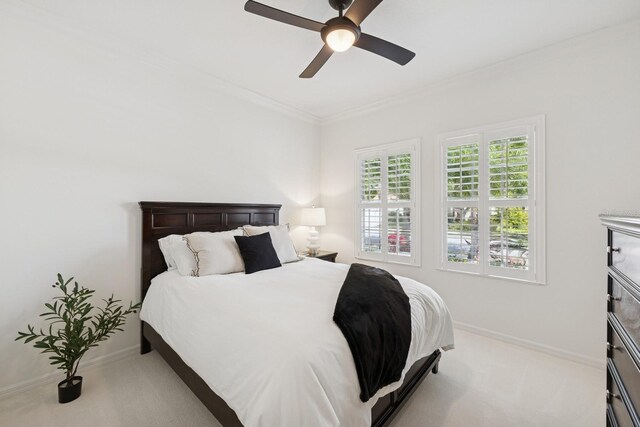 carpeted bedroom with a ceiling fan, ornamental molding, and baseboards
