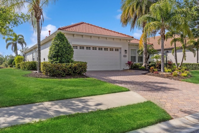 mediterranean / spanish-style home featuring driveway, an attached garage, a tile roof, and stucco siding