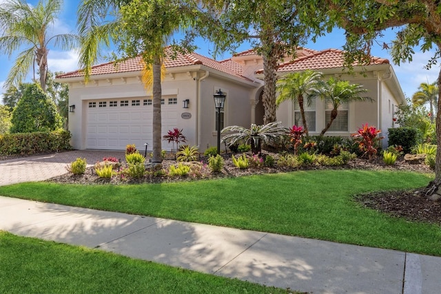 mediterranean / spanish-style house featuring a tiled roof, an attached garage, a front yard, stucco siding, and driveway