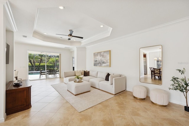 living room with a raised ceiling, ornamental molding, and ceiling fan with notable chandelier