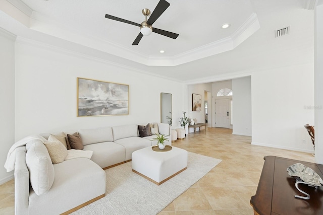 living area featuring visible vents, baseboards, ornamental molding, a ceiling fan, and a raised ceiling