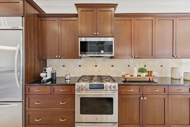 kitchen with brown cabinetry, decorative backsplash, appliances with stainless steel finishes, and dark stone counters