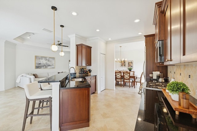 kitchen with a sink, a kitchen bar, a peninsula, open floor plan, and stainless steel microwave