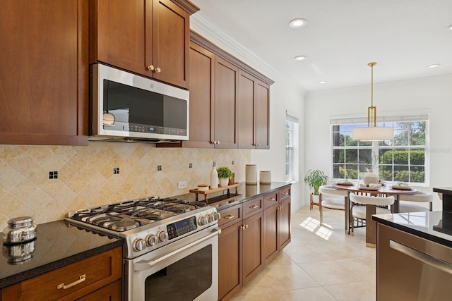kitchen featuring crown molding, appliances with stainless steel finishes, dark stone countertops, light tile patterned floors, and decorative backsplash