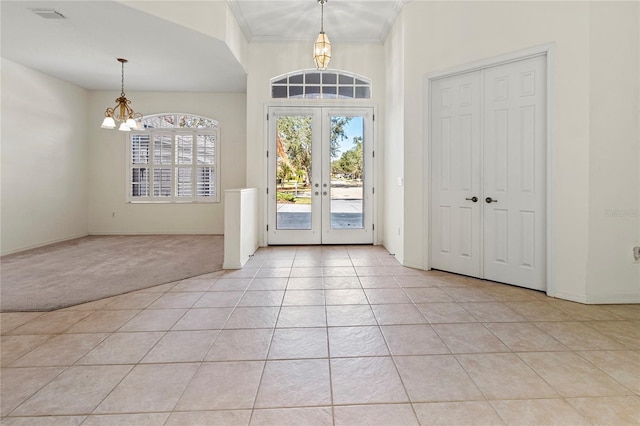 entrance foyer with light carpet, a notable chandelier, crown molding, and french doors