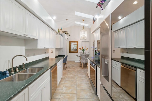 kitchen with sink, white cabinetry, an inviting chandelier, stainless steel appliances, and vaulted ceiling with skylight