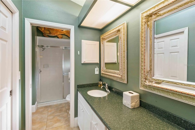 bathroom with vanity, tile patterned flooring, a shower with shower door, and toilet