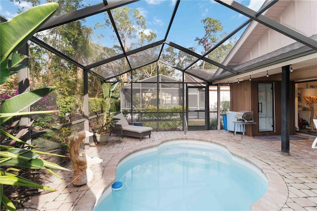 view of swimming pool featuring a patio area and glass enclosure