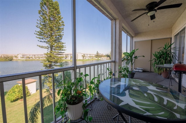 sunroom / solarium featuring a water view and ceiling fan