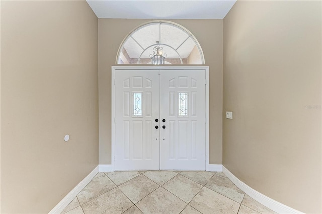 tiled entrance foyer featuring an inviting chandelier