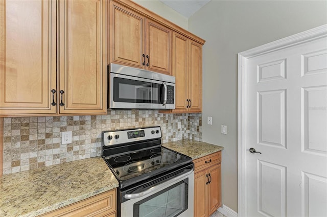 kitchen with light stone counters, appliances with stainless steel finishes, and decorative backsplash