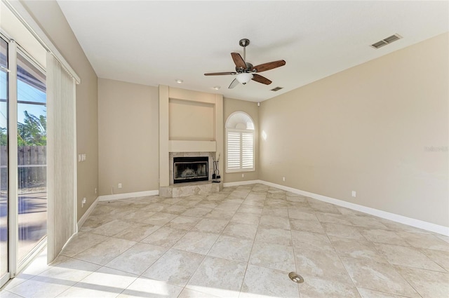 unfurnished living room featuring a tiled fireplace, light tile patterned floors, and ceiling fan