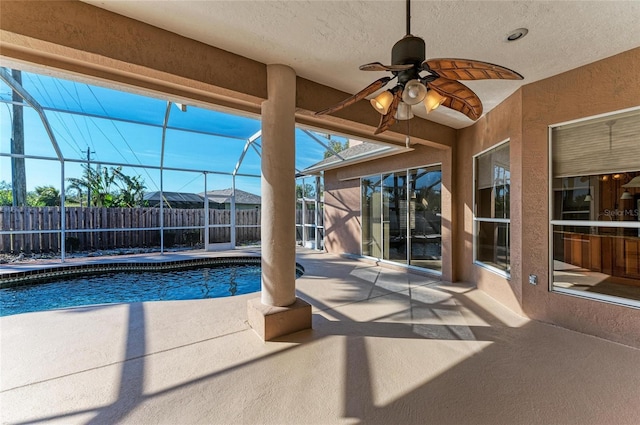 view of pool featuring ceiling fan, glass enclosure, and a patio area