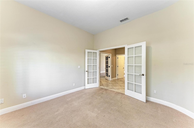 carpeted spare room featuring french doors