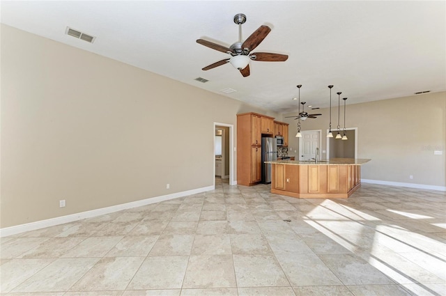 kitchen with pendant lighting, sink, ceiling fan, stainless steel appliances, and light stone countertops