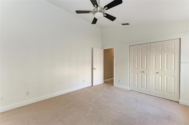 unfurnished bedroom featuring vaulted ceiling, light colored carpet, ceiling fan, and a closet