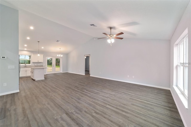 unfurnished living room with sink, dark wood-type flooring, ceiling fan with notable chandelier, and lofted ceiling