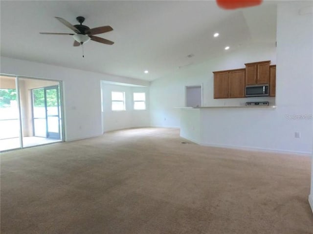 unfurnished living room featuring ceiling fan, plenty of natural light, light carpet, and lofted ceiling