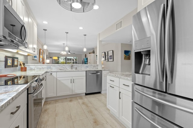 kitchen with pendant lighting, stainless steel appliances, kitchen peninsula, and white cabinets