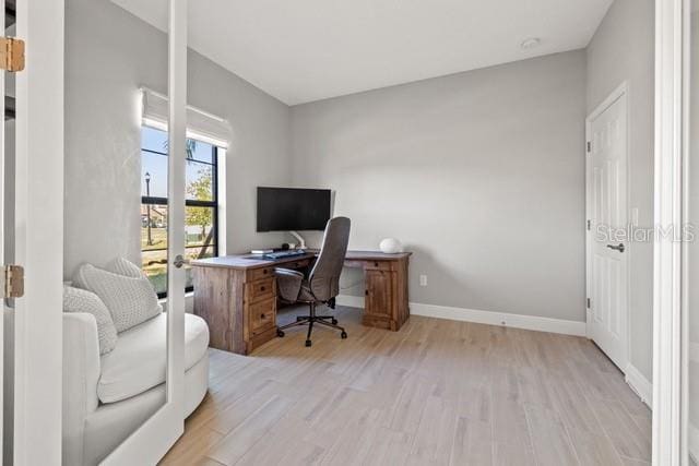 home office with light hardwood / wood-style floors and french doors