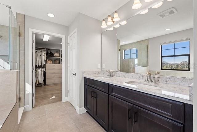 bathroom with a shower with shower door, tile patterned floors, and vanity