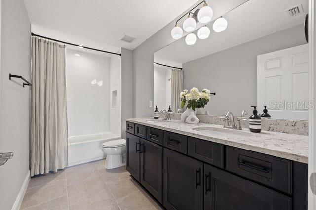 full bathroom featuring vanity, toilet, shower / bathtub combination with curtain, and tile patterned flooring