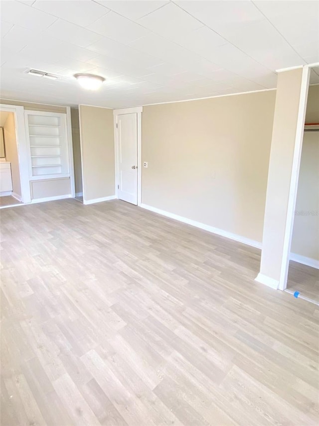 unfurnished room featuring built in shelves and light hardwood / wood-style flooring