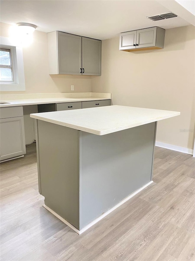 kitchen featuring light wood-type flooring, a center island, and gray cabinetry