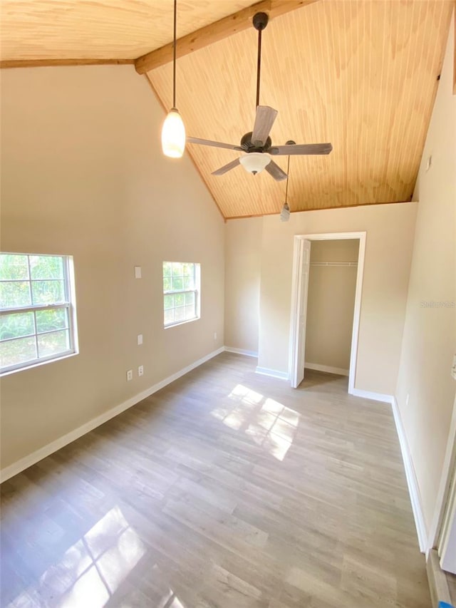 empty room with high vaulted ceiling, plenty of natural light, wood-type flooring, and beamed ceiling