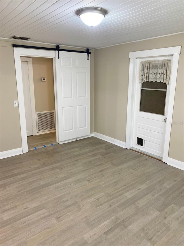 unfurnished bedroom with light hardwood / wood-style floors, a closet, and a barn door