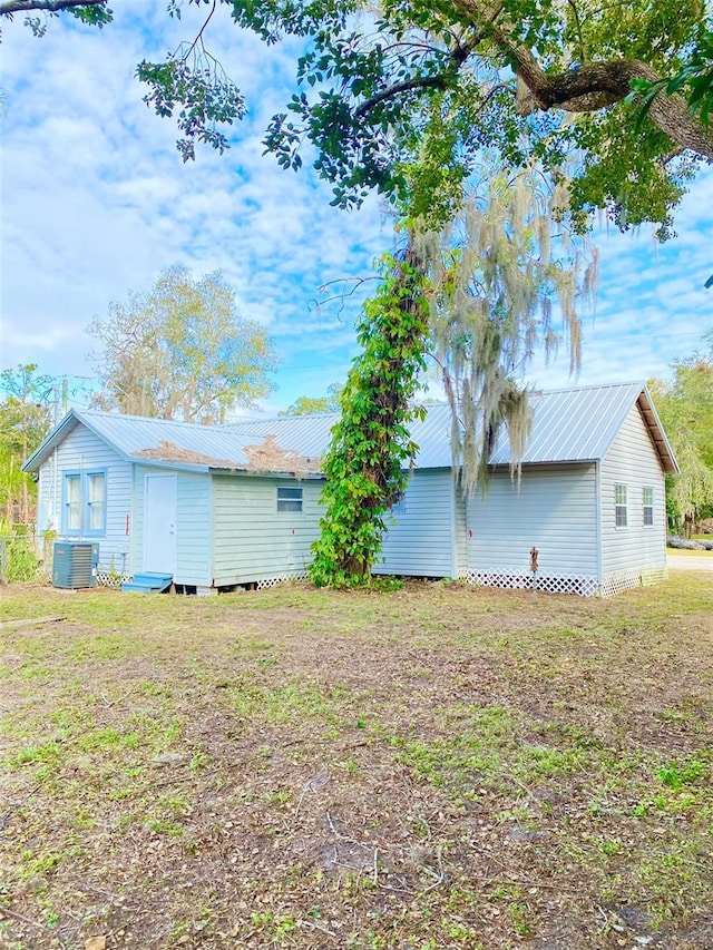 view of side of home with cooling unit and a lawn