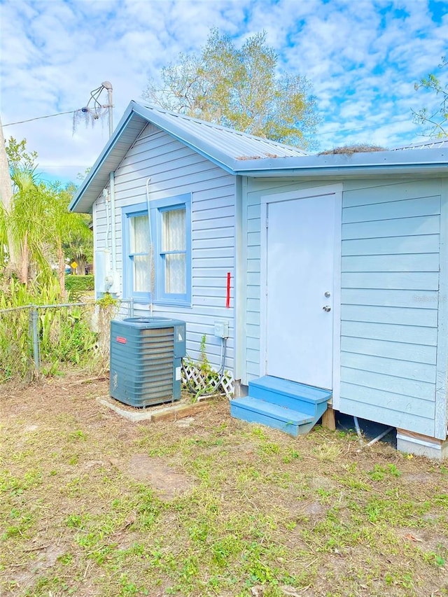 rear view of house with central air condition unit, a yard, and a storage unit