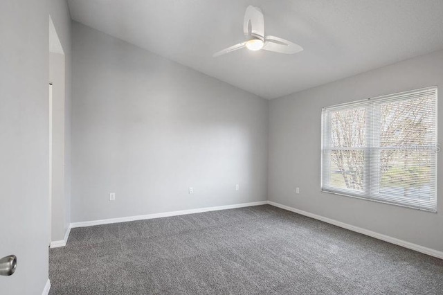 unfurnished room with ceiling fan and dark carpet