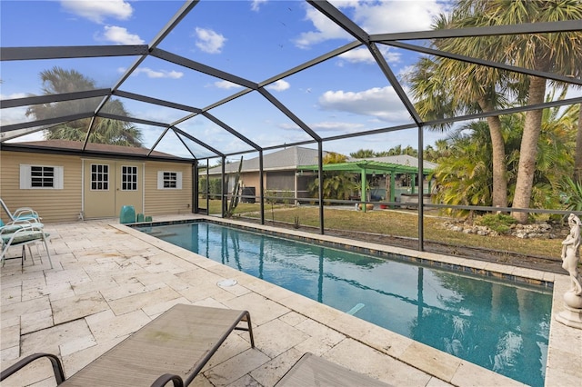 view of pool featuring a patio, glass enclosure, and an outdoor structure