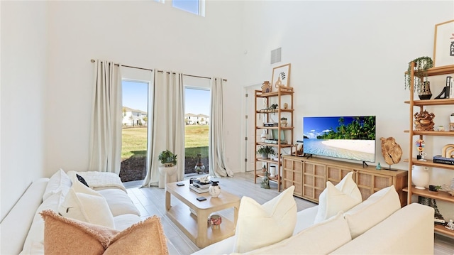 living area featuring a towering ceiling, wood finished floors, and visible vents