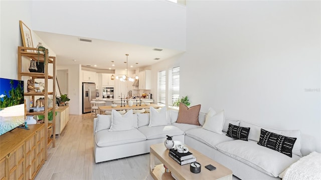 living room with a chandelier, visible vents, and light wood finished floors