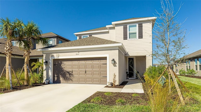 view of front of home with a shingled roof, concrete driveway, an attached garage, and stucco siding