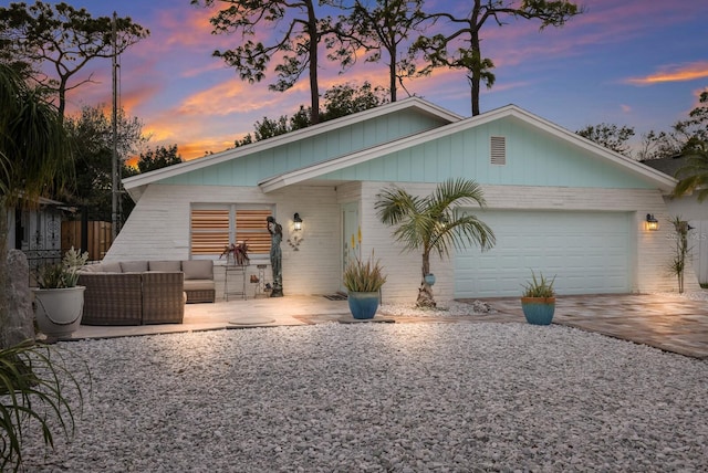 back house at dusk with a garage, an outdoor hangout area, and a patio