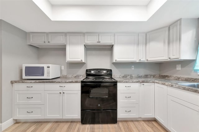 kitchen with a raised ceiling, white cabinetry, black electric range oven, and light wood-type flooring