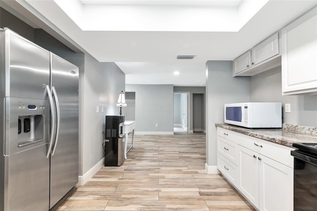 kitchen featuring stainless steel refrigerator with ice dispenser, white cabinetry, light stone counters, and electric range oven